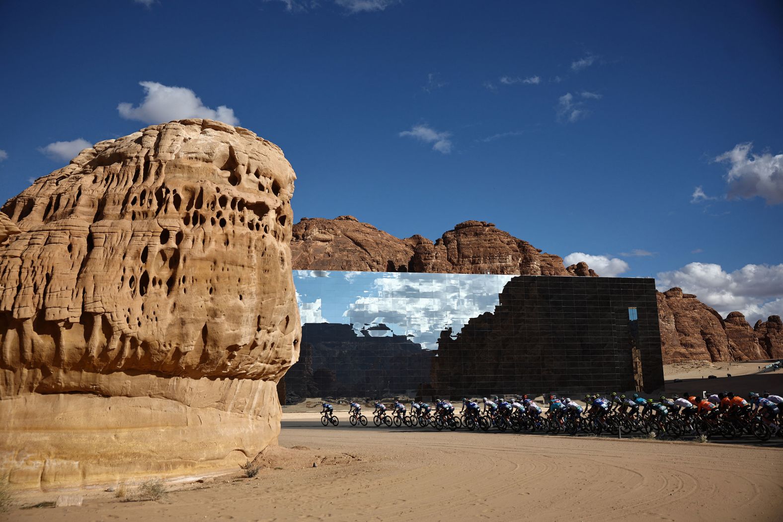 A pack of cyclists rides in front of the Maraya, the world’s largest mirrored building, during the fourth stage of the AlUla Tour in Saudi Arabia on Friday, February 2.