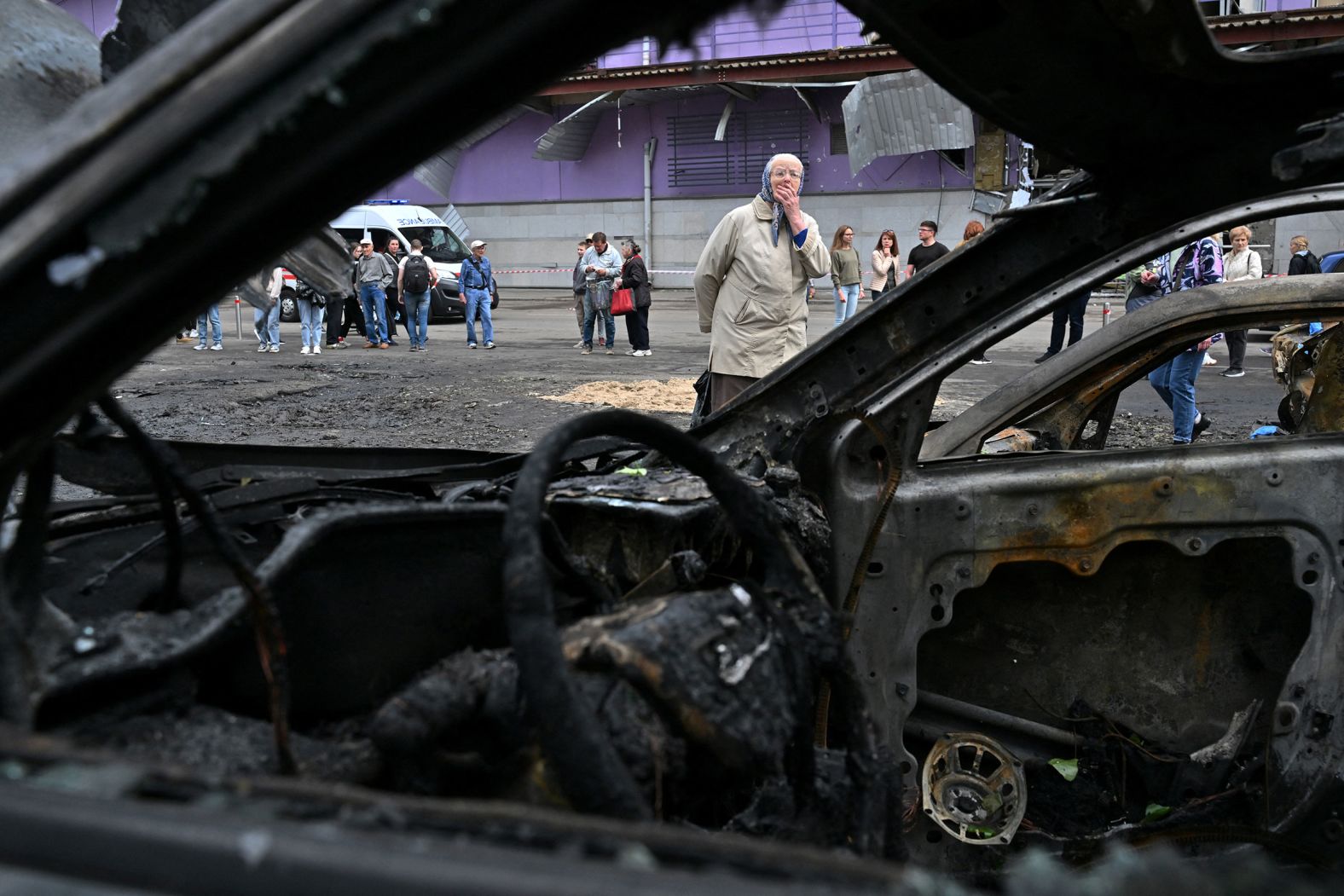 A woman reacts as she looks at burned cars outside a mall following a night- time drone attack in Kyiv, Ukraine, on Sunday, May 4.