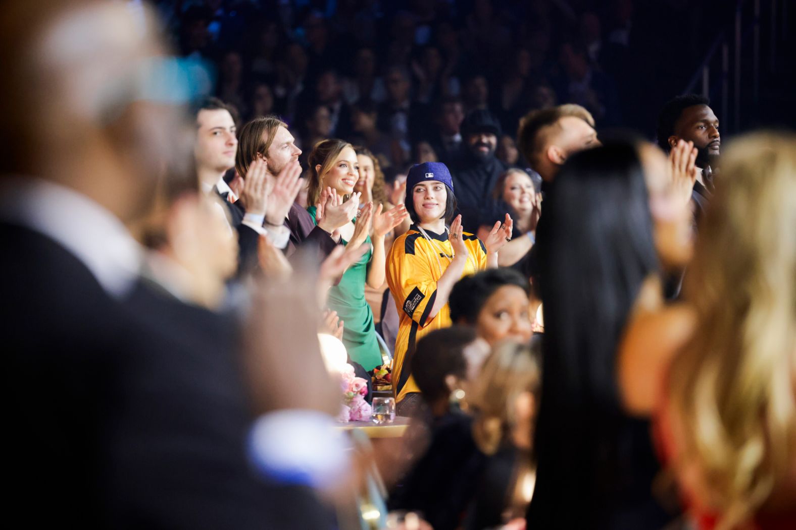 Billie Eilish, in the blue Los Angeles Dodgers hat, joins others applauding during the show.