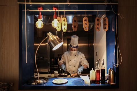 A chef wears a protective face mask with a shield as he prepares breakfast at a hotel in the "closed loop" on February 4.