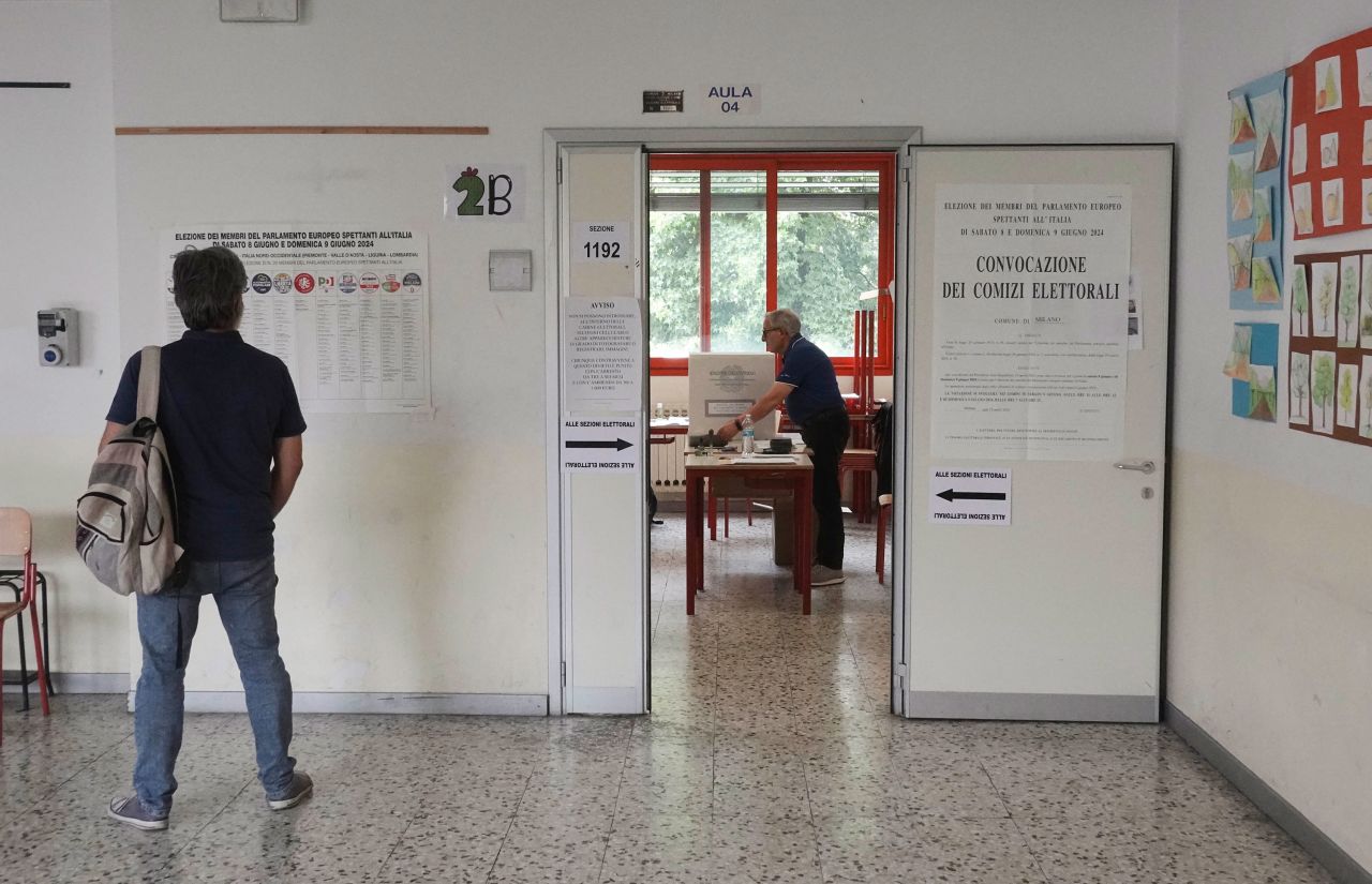 A man checks an electoral board before entering a polling station in Milan on June 9.