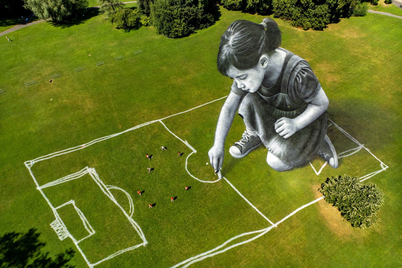 People play on a field in Geneva, Switzerland, that was painted by the artist Saype on Monday, June 30.