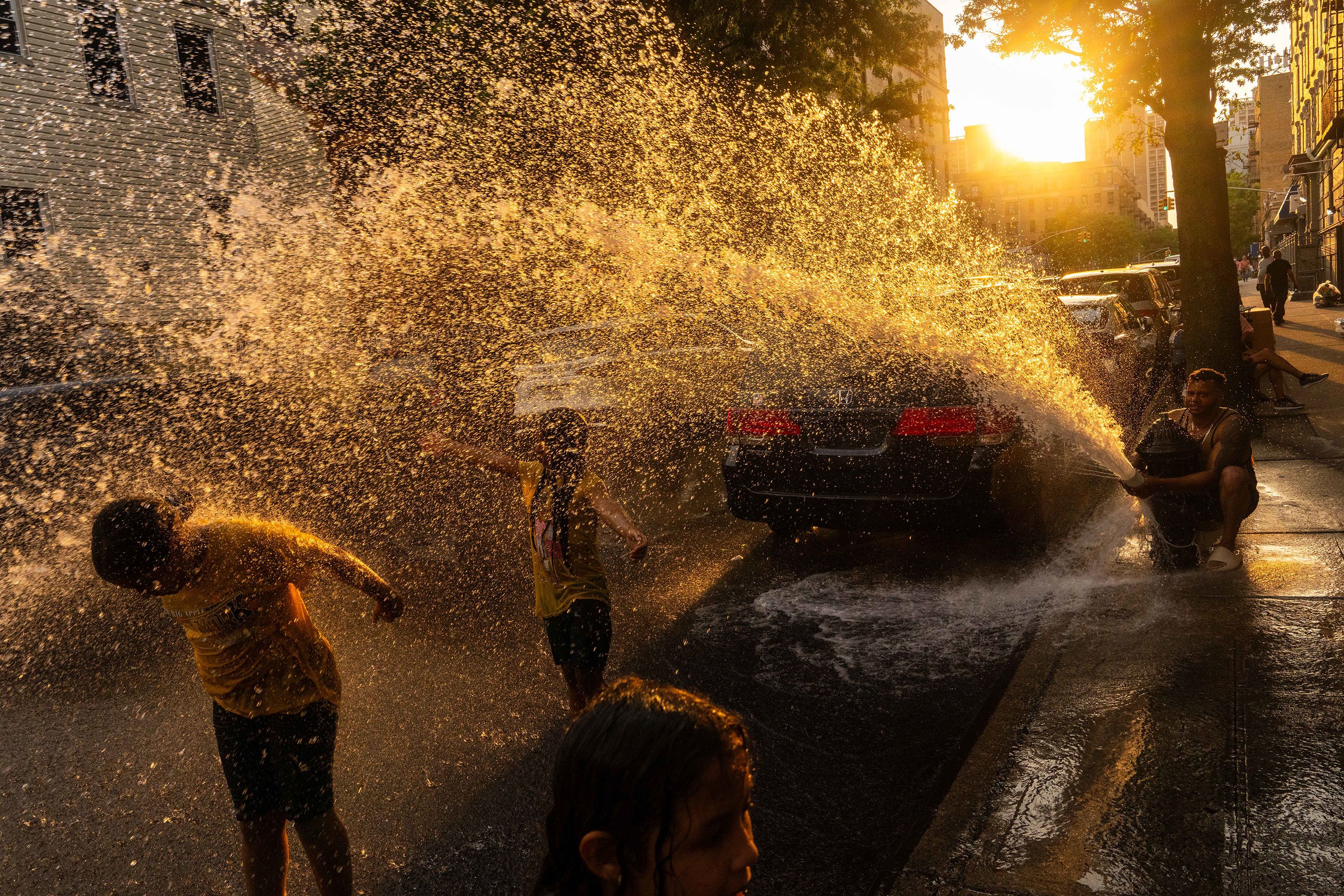 Cousins Miranda, Elianna and Isabella cool off with water from a fire hydrant during a hot day in New York on Tuesday, July 16.