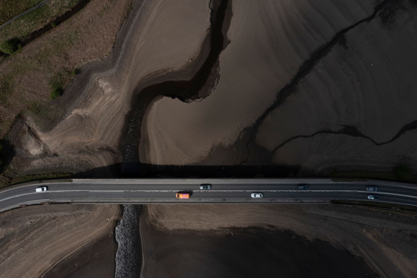 In this aerial photo, taken on Monday, May 19, vehicles cross a bridge at the Woodhead Reservoir in Derbyshire, England. England is experiencing a significant drought, with reservoir levels at 84% of capacity.