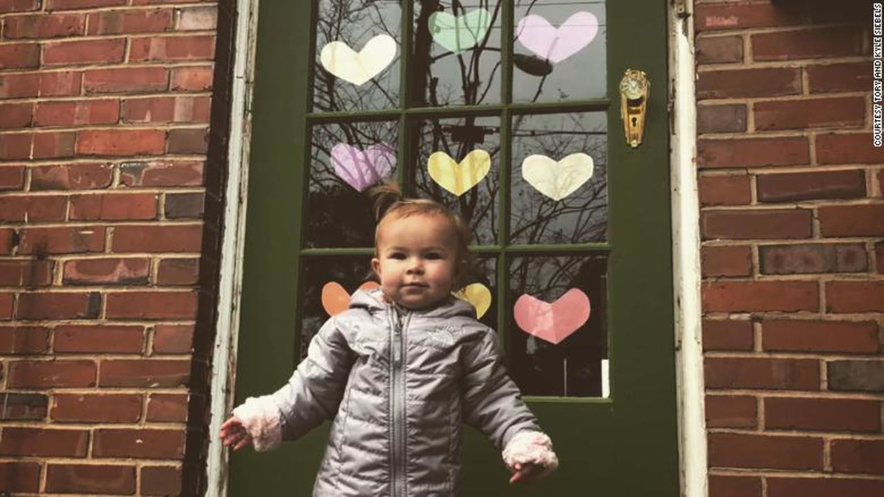 Nora Siebels stands outside her front door decked out in paper hearts in Norfolk, Virginia.