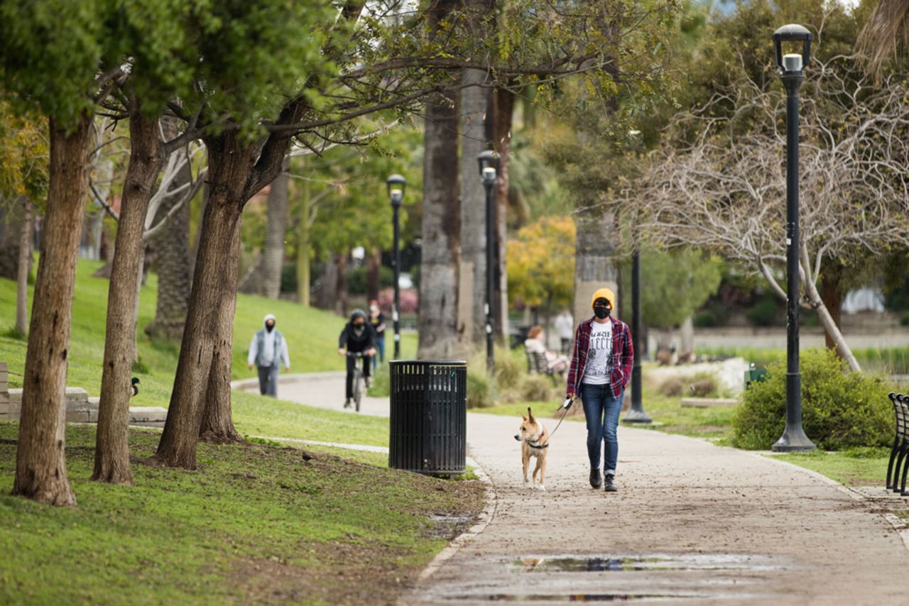 Pedestrians walk around Echo Park Lake wearing face masks on April 8, in Los Angeles. 