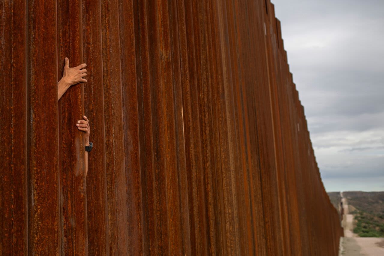 A smuggler scales the border wall from Sonora, Mexico, as photographed from Ruby, Arizona, on June 26. 