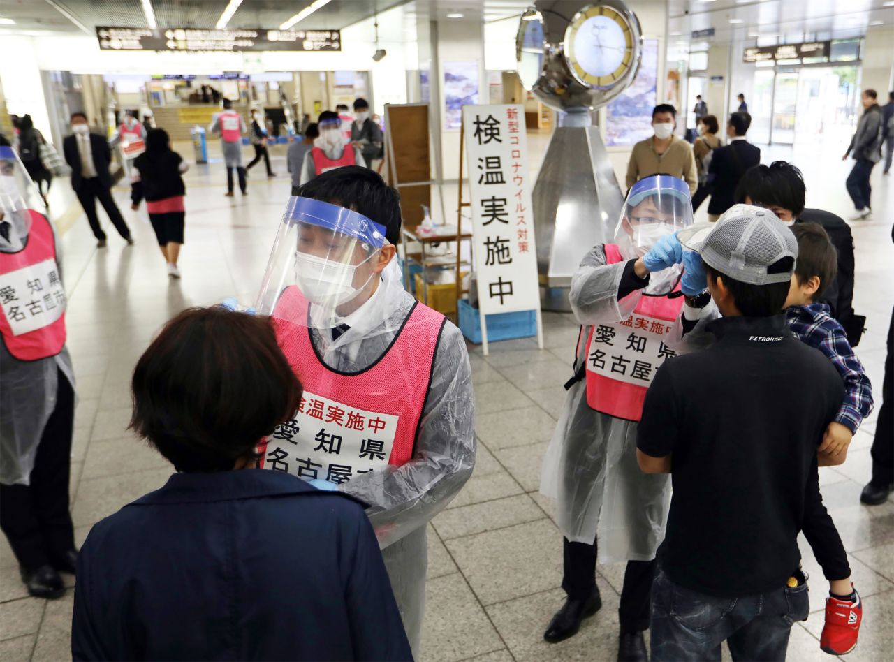 Staff members of Aichi Prefecture check the body temperature of passengers arriving at Nagoya railway station on April 29.