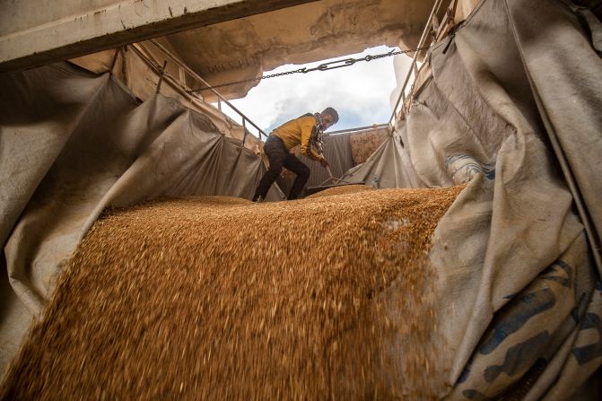 A worker rakes wheat as it’s unloaded at a silo in Qamishli, Syria, on Thursday, June 12.