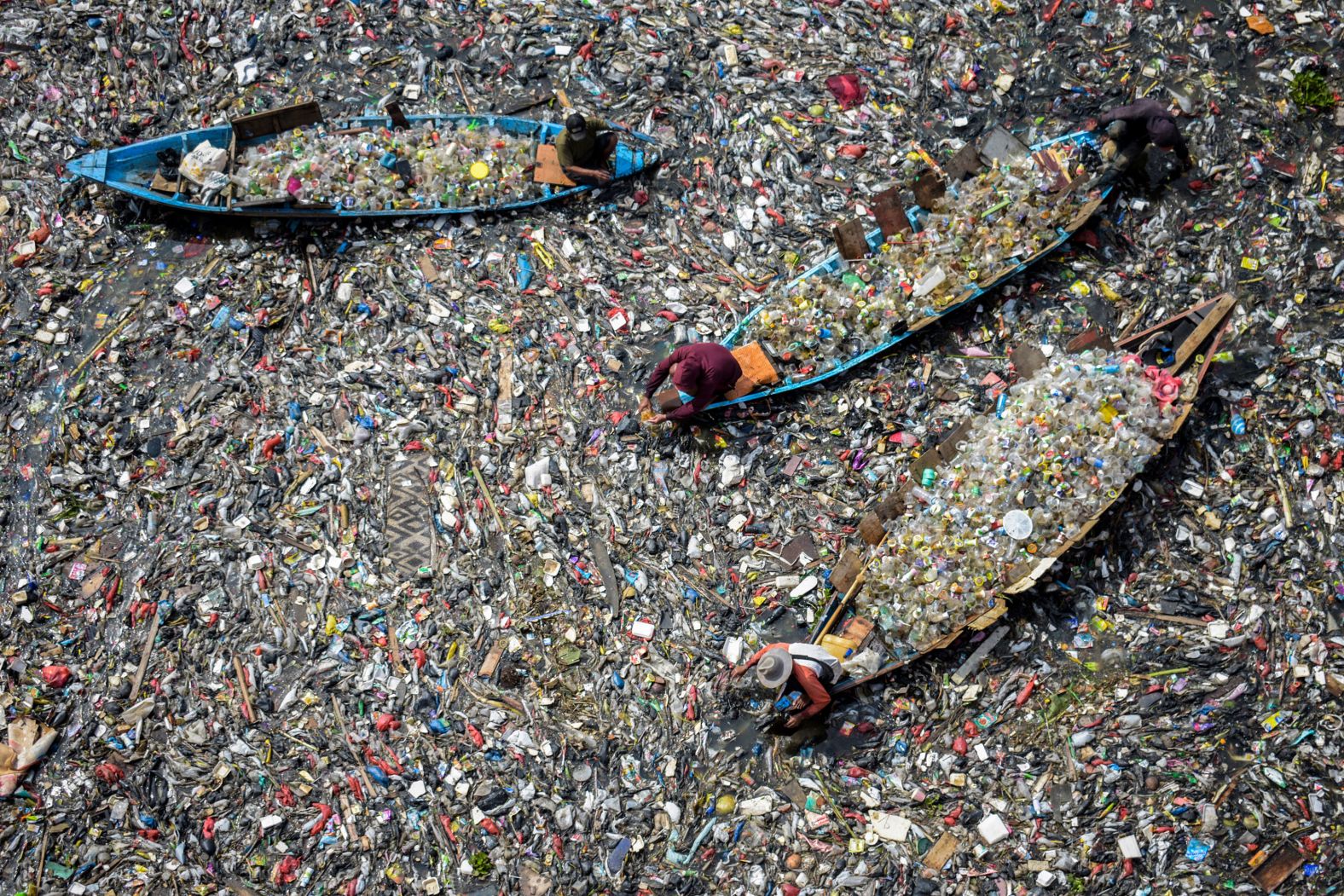 People on boats collect recyclable plastics from the heavily polluted Citarum River in Bandung, Indonesia, on Wednesday, June 12.