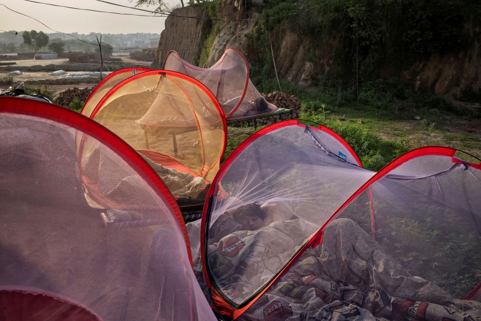Yaseen, a 15-year-old boy, sleeps inside a tent during a heat wave that forced villagers in a brick-making settlement to seek shelter outdoors in Islamabad, Pakistan, on Friday, May 16.