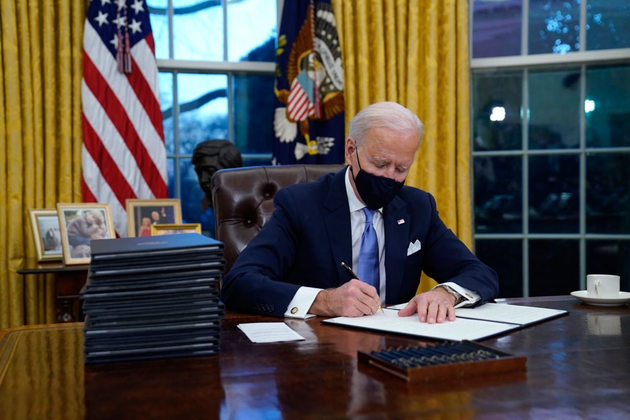 President Joe Biden signs his first executive order in the Oval Office of the White House on January 20.