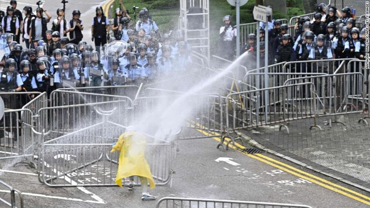 Police officers use a water canon on a lone protestor near the government headquarters.