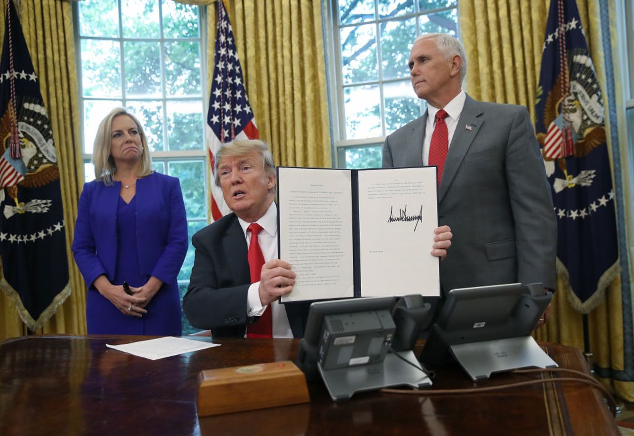 President Trump, accompanied by Department of Homeland Security Secretary Kirstjen Nielsen (L) and U.S. Vice President Mike Pence (R), displays an executive order on June 20, 2018 in Washington, DC.