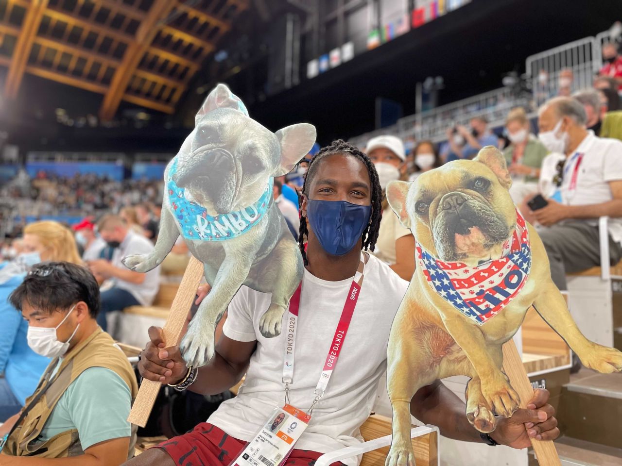 Scott Evans, host of Access Hollywood, displays cardboard cutouts of Simone Bile's dogs, during the women's balance beam final on Tuesday.