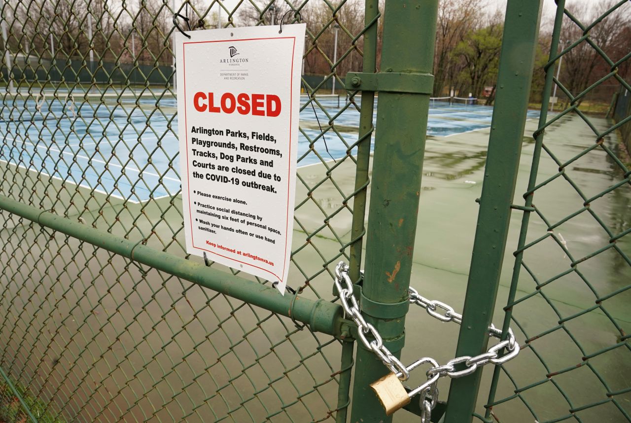 A locked gate and sign warns residents that the tennis courts are closed due to coronavirus health and safety measures in Bluemont Park, Arlington, Virginia, on March 25.