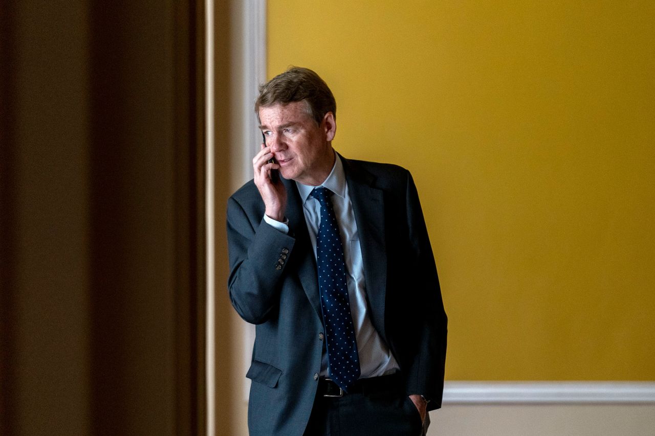 Sen. Michael Bennet speaks on a cellphone in a hallway as the House approved a 45-day funding bill to keep federal agencies open, on Saturday.