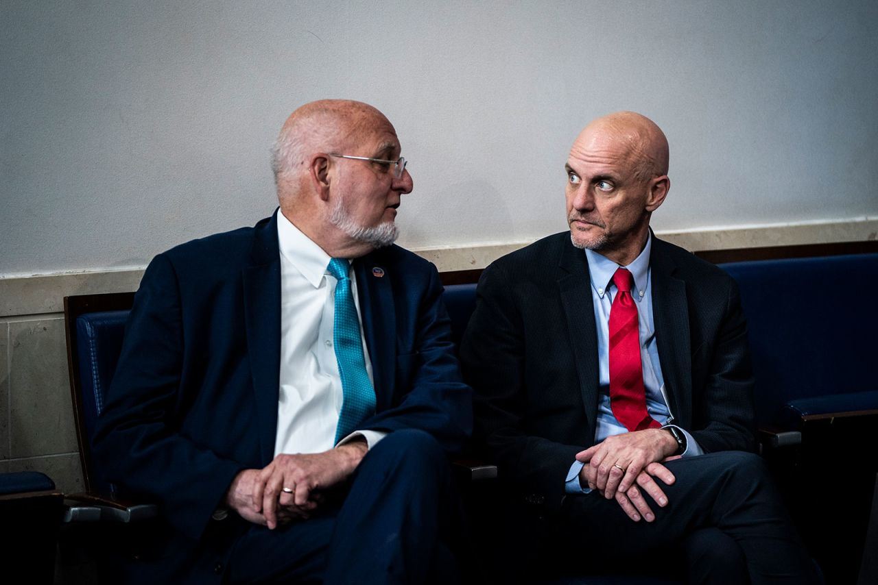 CDC Director Robert Redfield whispers to Food and Drug Administration Commissioner Dr. Stephen Hahn during a coronavirus task force briefing.