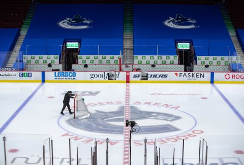 An arena worker removes the net from the ice after the Vancouver Canucks and Calgary Flames NHL hockey game was postponed due to a positive COVID-19 test result, in Vancouver, British Columbia, on March 31.