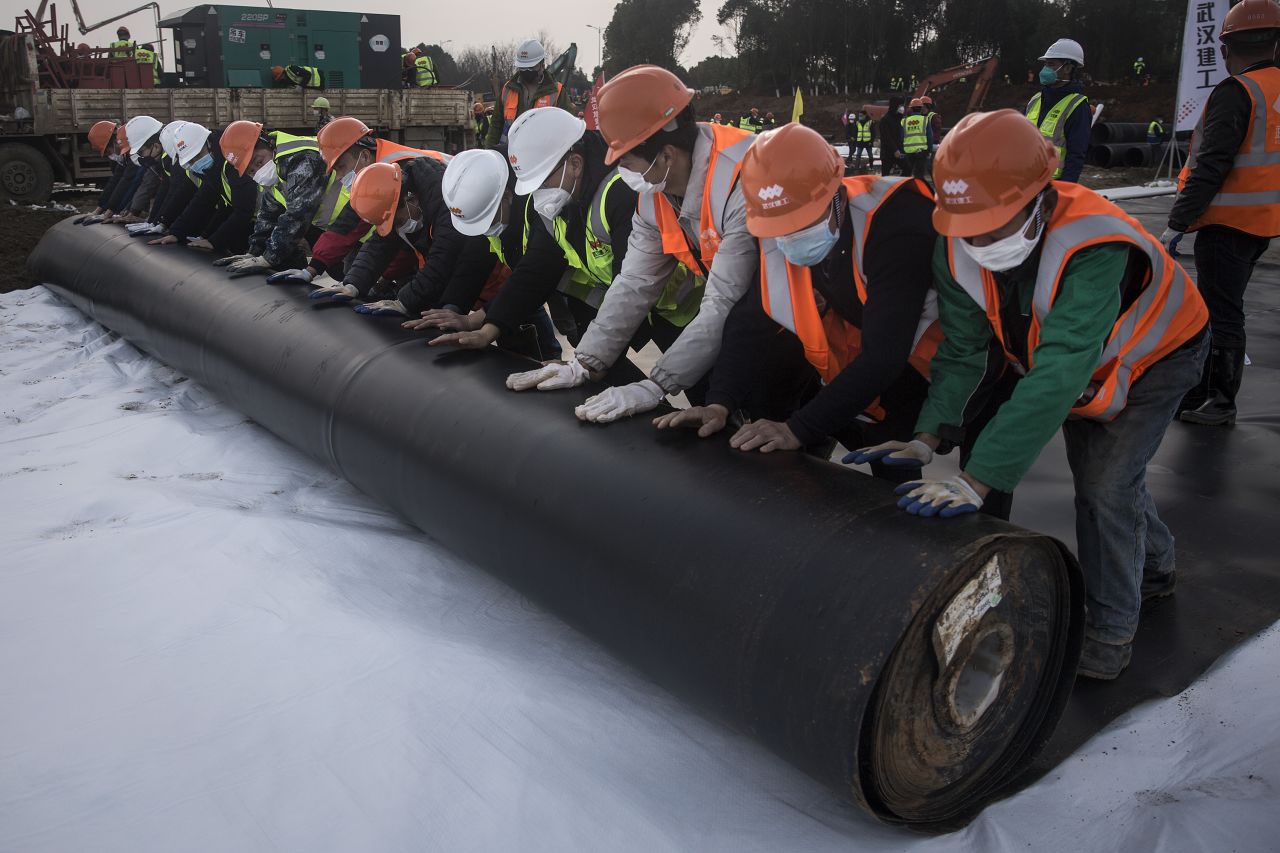 Construction workers roll out damp proof lining at the new hospital in Wuhan.