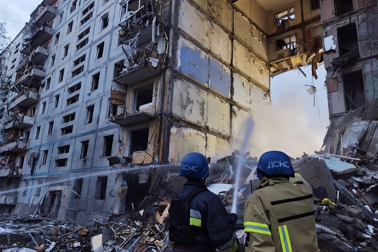 Rescuers use a hose to extinguish a fire in a residential building damaged after a strike in Zaporizhzhia, on October 9.