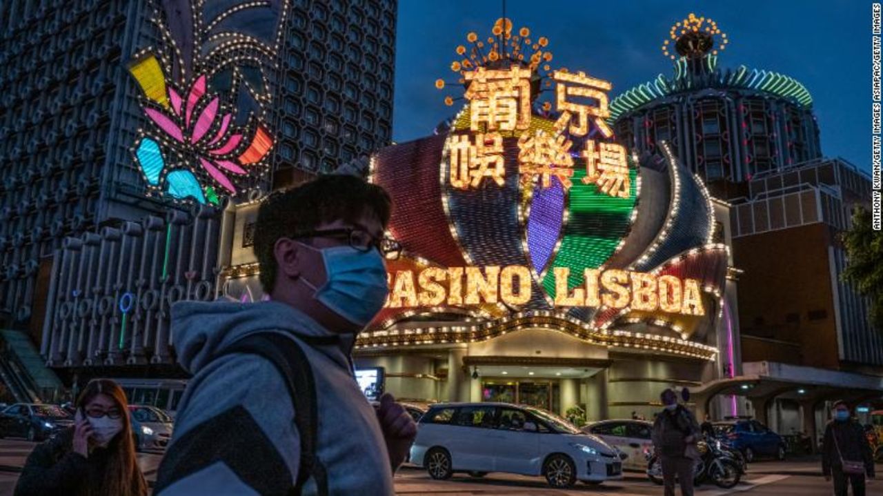 People wearing face masks walk in front of the Grand Lisboa Hotel on January 28 in Macao.