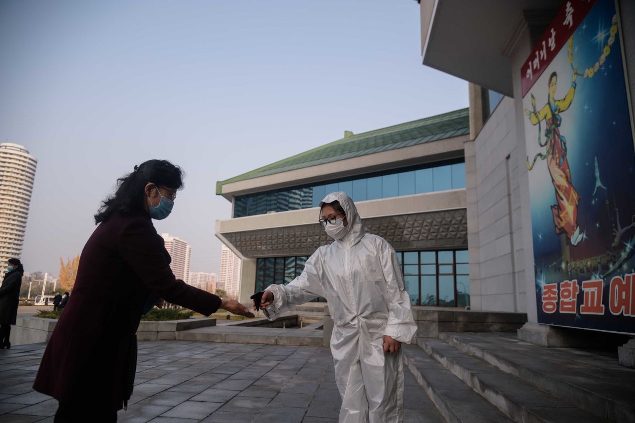 As part of preventative measures against coronavirus, a worker takes the temperature of an attendee ahead of a performance by North Korea's National Acrobatic Troupe in Pyongyang, North Korea, on November 16. 