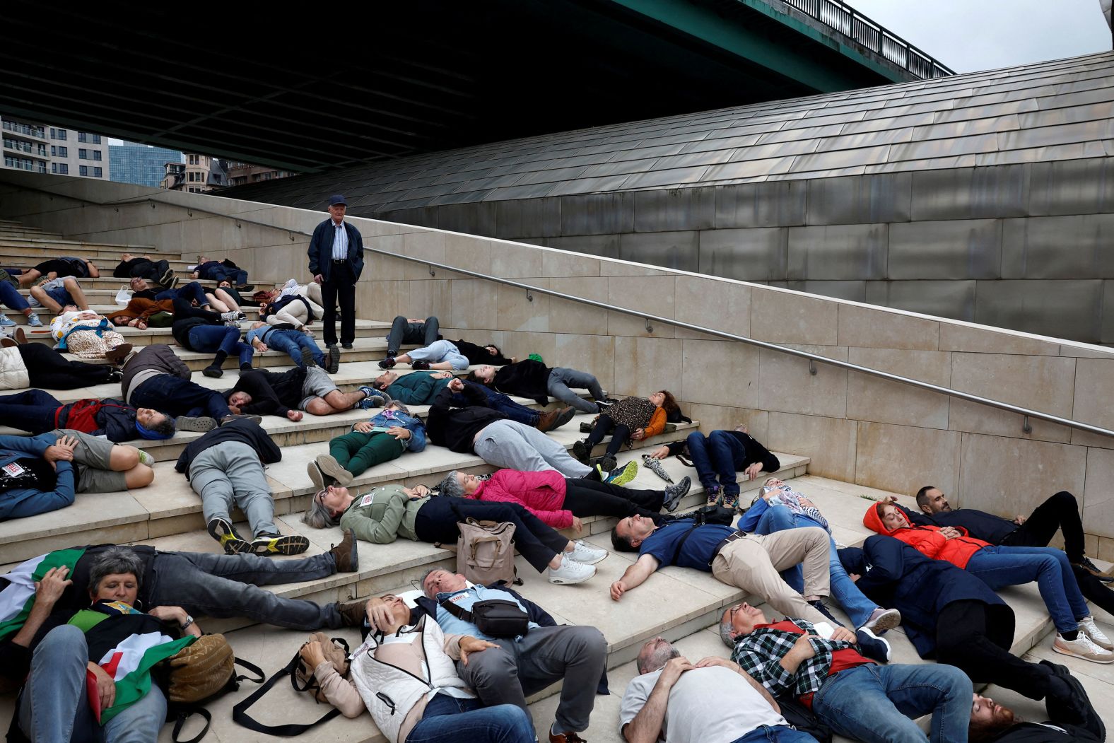 A man looks on as protesters lie on the ground outside the Guggenheim Museum in Bilbao, Spain, on Saturday, June 8. They were protesting the casualties in Gaza.