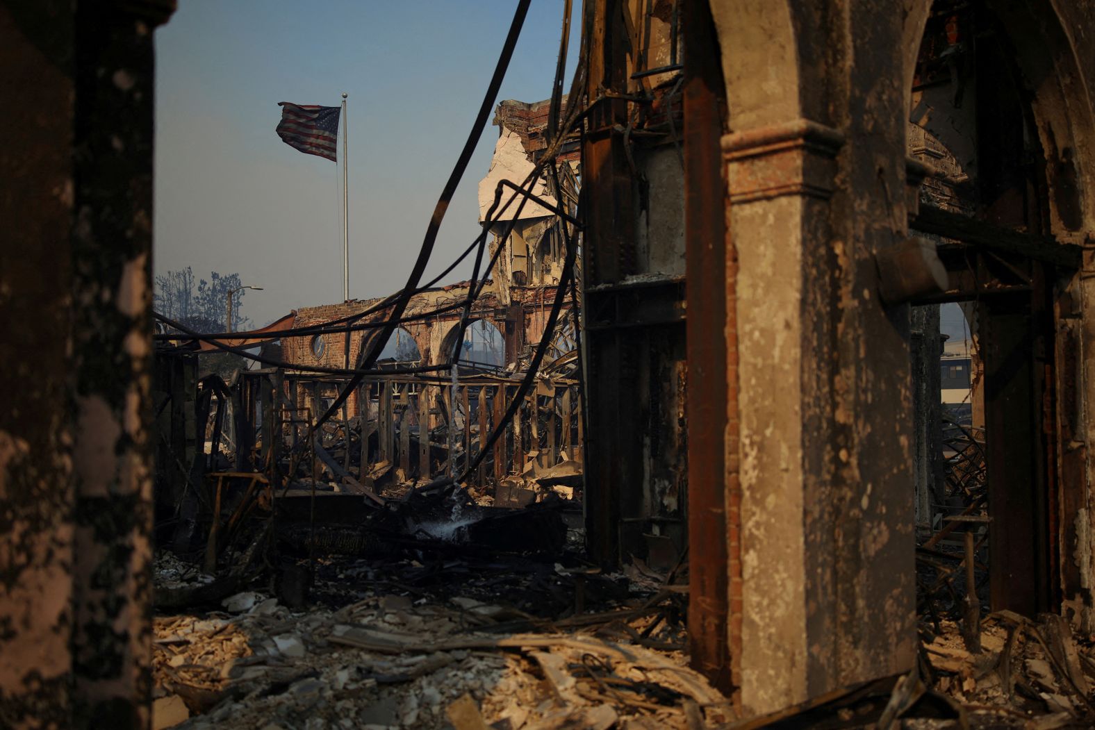 An American flag waves over a wildfire-burnt structure in Los Angeles on Wednesday, January 8.