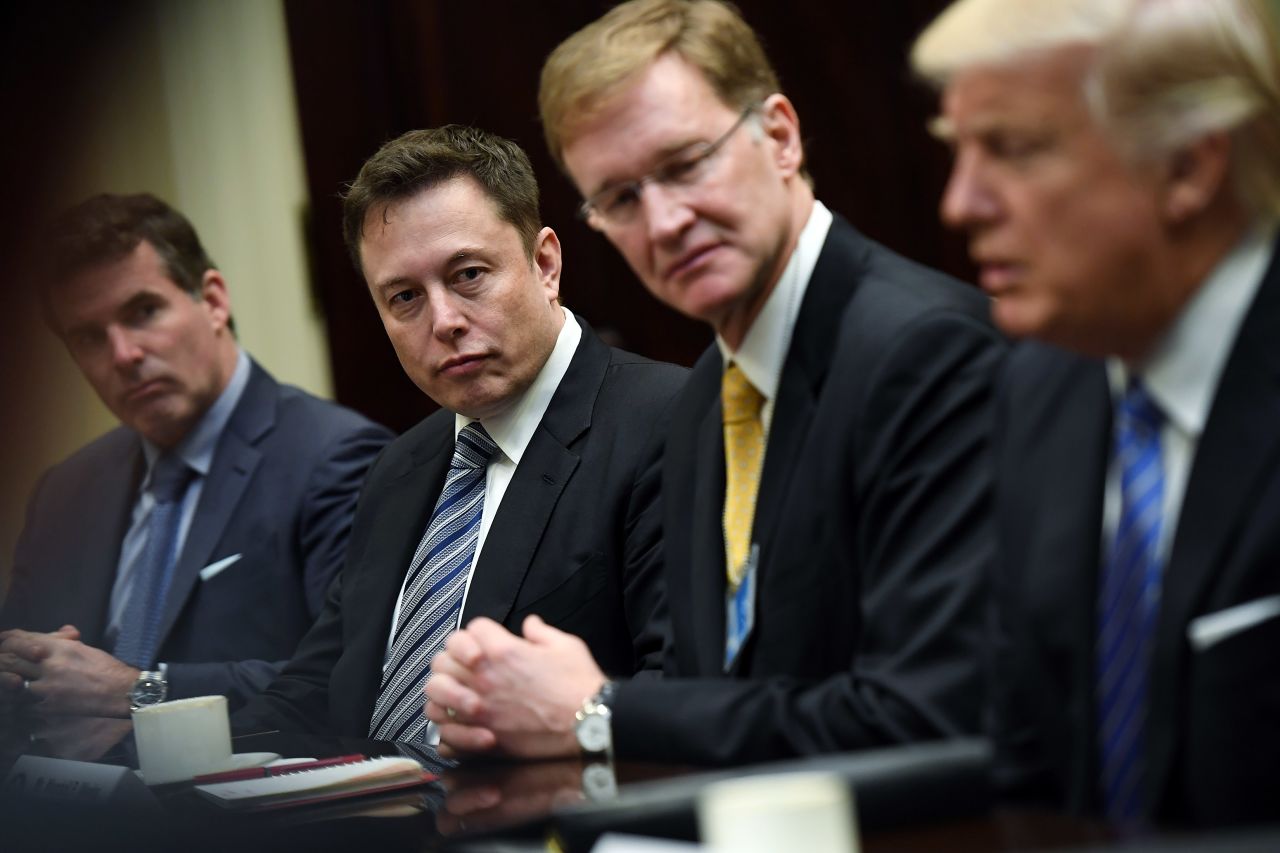 Elon Musk listens to then-President Donald Trump as he meets with business leaders at the White House in 2017.