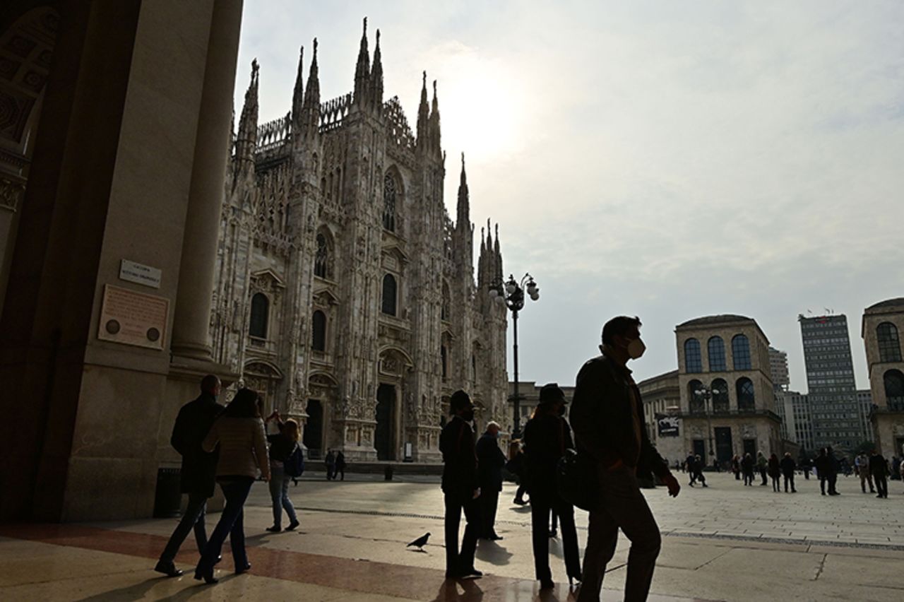 Milan on October 20, 2020 in front of the Duomo shows people walking across and wearing protective face masks. 