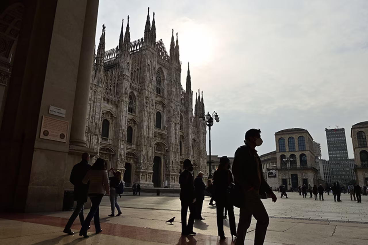 Milan on October 20, 2020 in front of the Duomo shows people walking across and wearing protective face masks. 