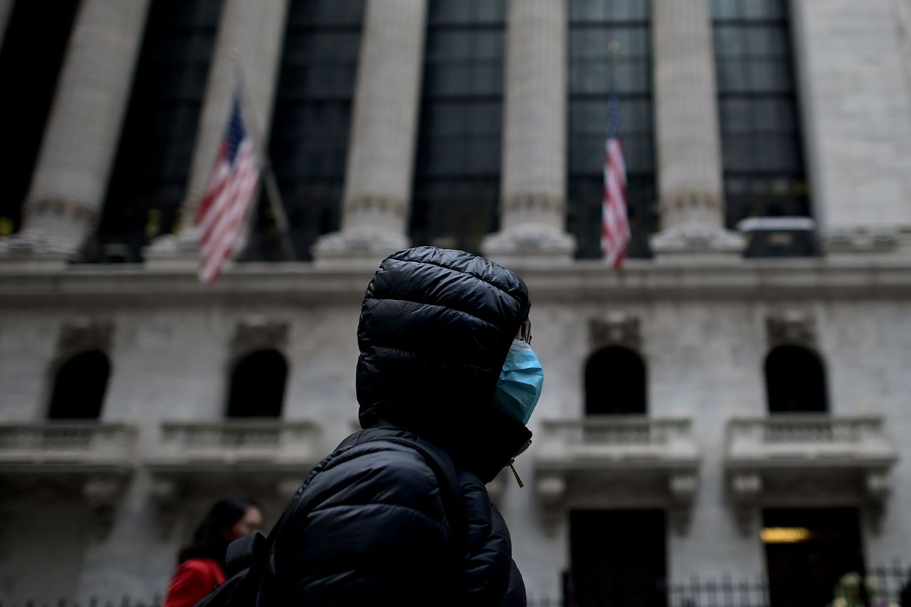 A person wearing a surgical mask walks past the New York Stock Exchange on February 3.