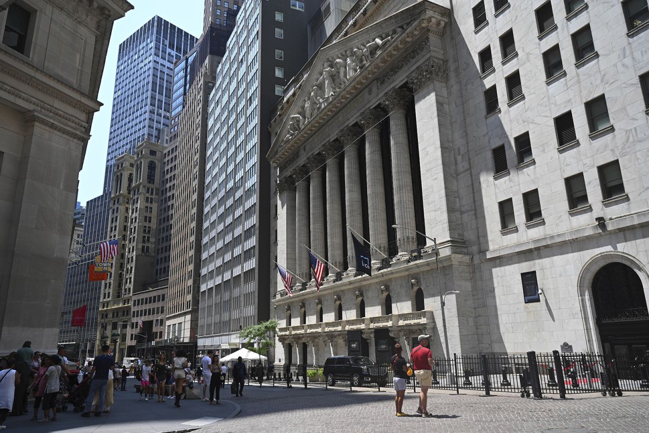 People walk past the New York Stock Exchange on Wall Street on July 11.