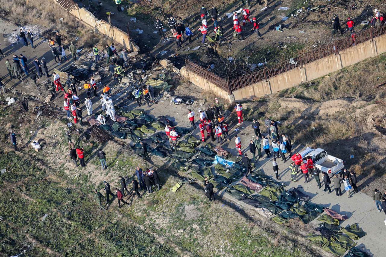 An overview of the crash scene shows emergency crews and body bags amid the plane's debris.