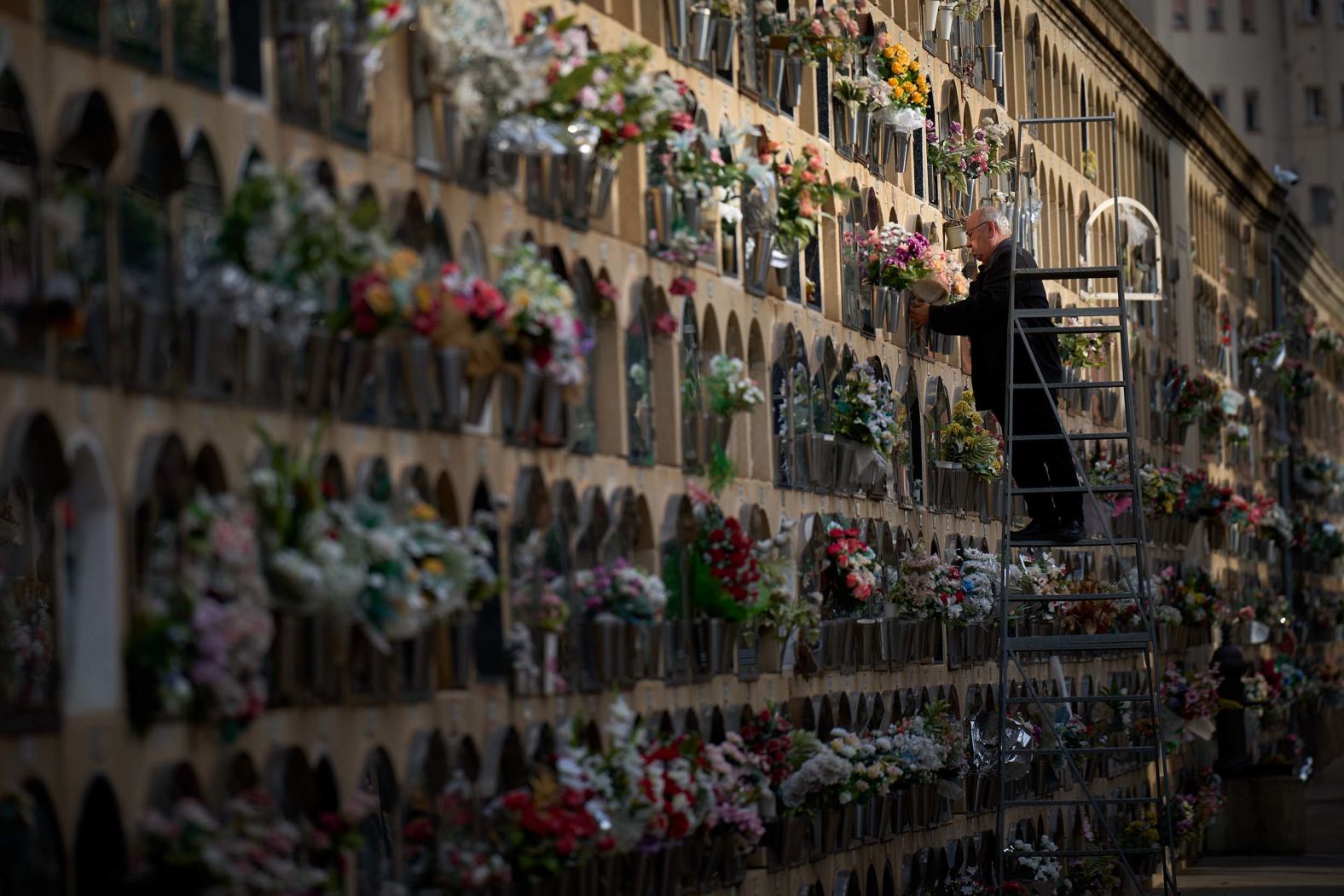 A man in Barcelona, Spain, places flowers on a grave on All Saints' Day, a Catholic holiday to honor saints and remember deceased relatives, on Saturday, November 1.