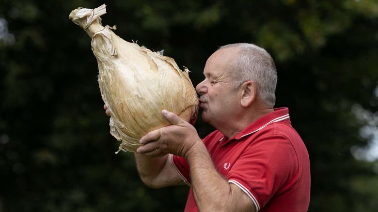 TOPSHOT - Stephen Purvis poses for a picture with his winning 8.8 kg onion which won the 'Heaviest Onion' category of the giant vegetable competition on the first day of the Harrogate Autumn Flower Show at Newby Hall country house, near Ripon, northern England, on September 19, 2025. (Photo by Oli SCARFF / AFP) (Photo by OLI SCARFF/AFP via Getty Images)          