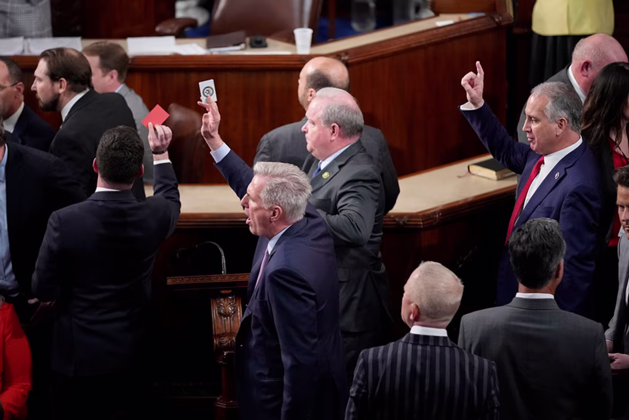 McCarthy holds a voting card in the air during a motion to adjourn that started after the 14th failed speakership vote. The House did not adjourn, and McCarthy was elected on the 15th vote.