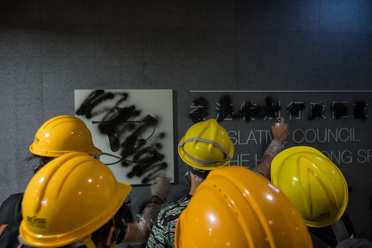 Protesters spray-paint graffiti on a sign at the Legislative Council building on July 1, 2019 in Hong Kong.
