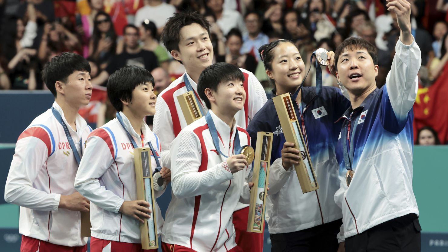 Athletes from North Korea and South Korea take a selfie after the Table Tennis Mixed Doubles medal matches in Paris on Tuesday