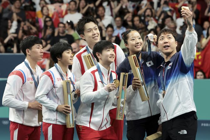 South Korean table tennis player Lim Jong-hoon <a >takes a selfie on the medal podium</a> with his mixed-doubles partner, Shin Yu-bin, and teams from China and North Korea on Tuesday, July 30. Lim and Shin won bronze. On the left is the North Korean team of Ri Jong-sik and Kim Kum-yong, who won the silver. At center is the Chinese team of Wang Chuqin and Sun Yingsha, who won the gold.