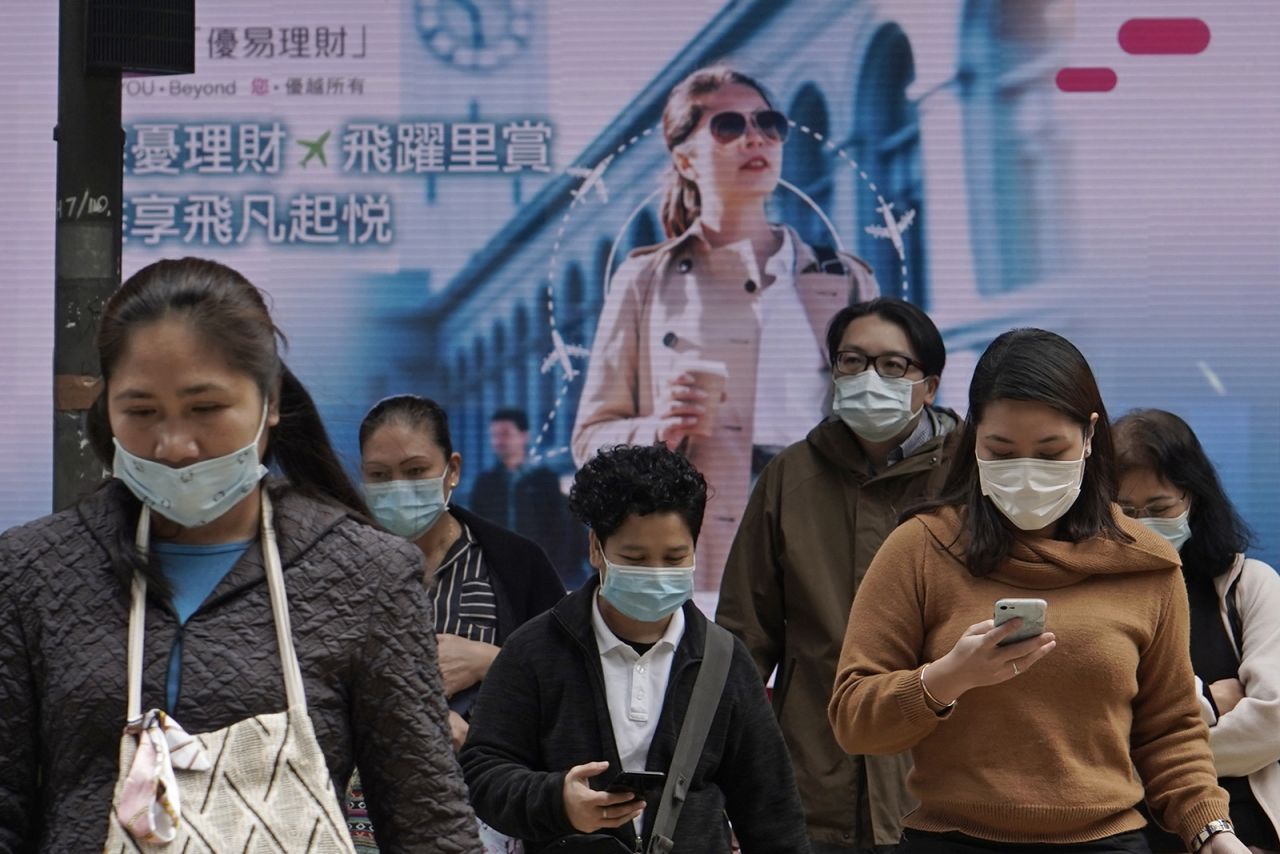 People wearing face masks walk on a street in Central, the business district of Hong Kong, on Tuesday, February 11.