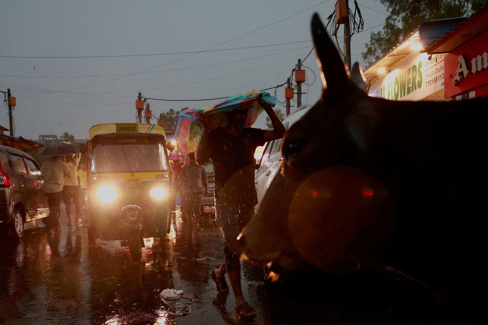 A man uses a cloth to cover himself from the rain as he walks through a wholesale market in New Delhi on Friday, May 2.
