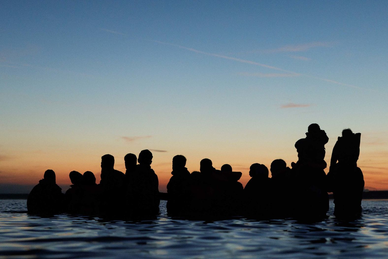 Migrants wade into the water in Gravelines, France, to get to a “taxi boat” as they look to cross the English Channel at dawn on Friday, September 19. <a href="index.php?page=&url=https%3A%2F%2Fwww.cnn.com%2F2025%2F09%2F18%2Fworld%2Fgallery%2Fphotos-this-week-september-11-september-18">See last week in 34 photos</a>.