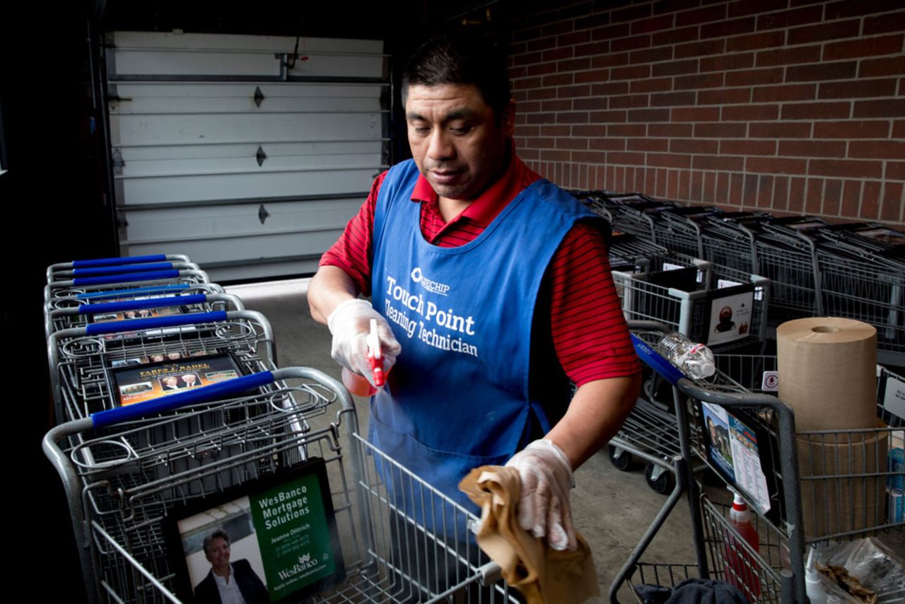 Desiderio Reynoso Morales disinfects shopping carts before they are used by patrons at Kroger on Tuesday, April 7, in Newport, Kentucky.