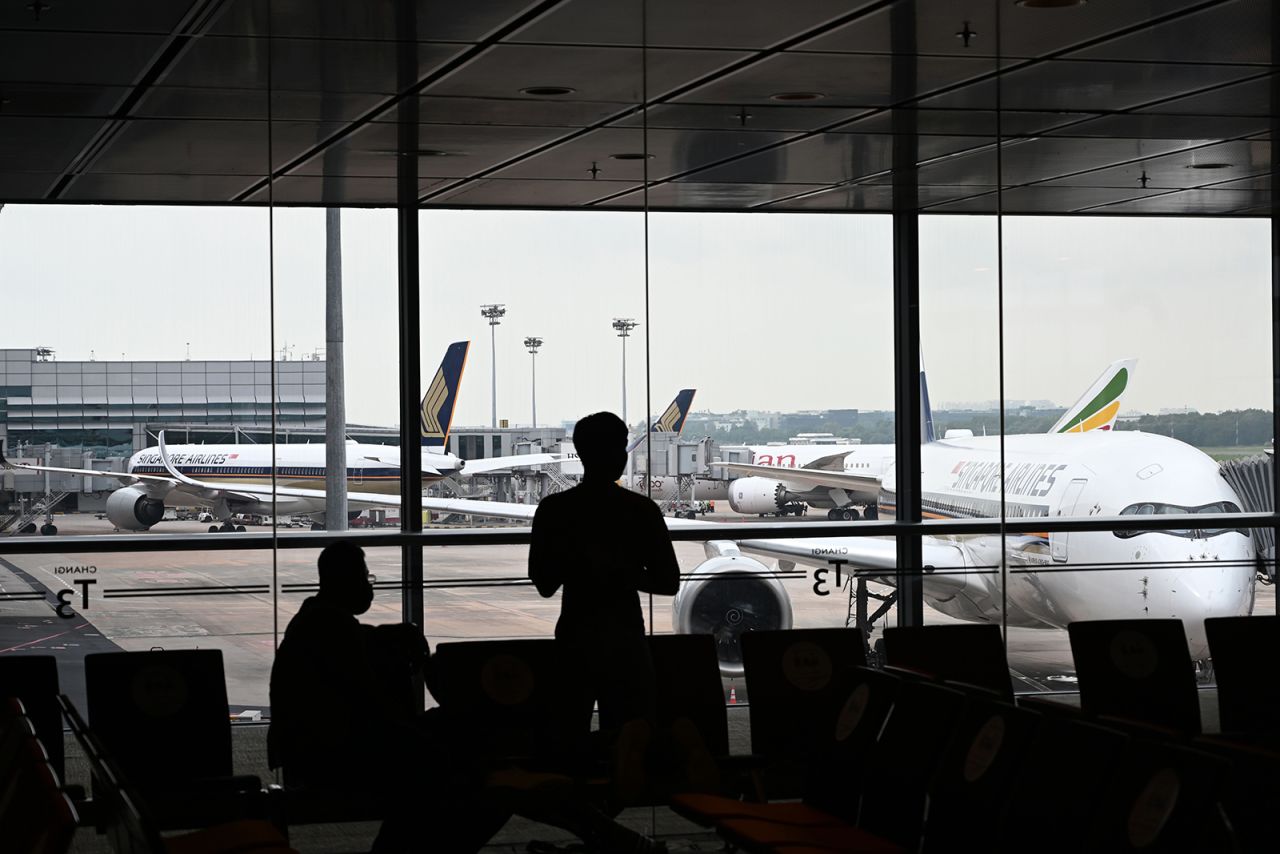 People are silhouetted against Singapore Airlines Airbus planes at Changi International Airport in Singapore on October 24. 