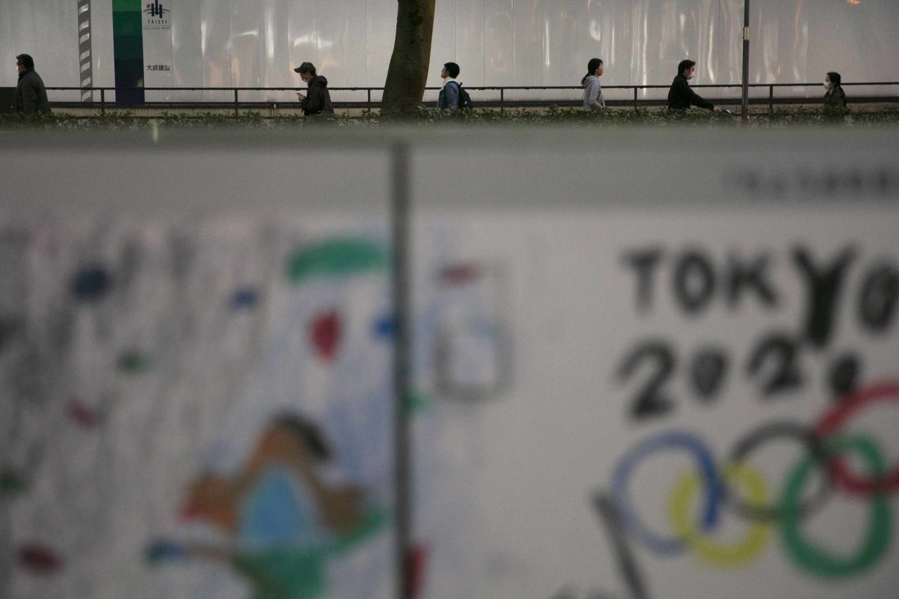 Commuters in Tokyo make their way past a poster celebrating the Tokyo 2020 Olympics, foreground, on Tuesday.