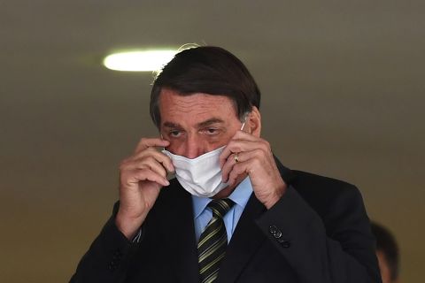 Brazilian President Jair Bolsonaro fixes his face mask before the event "Brazil beating Covid-19" at Planalto Palace in Brasilia, on August 24.