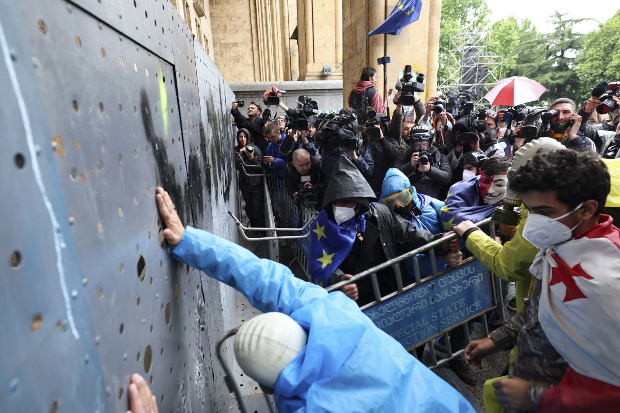 Georgian demonstrators attempt to break into the parliament through a metal barrier erected in front of its main gates, during a rally against the controversial