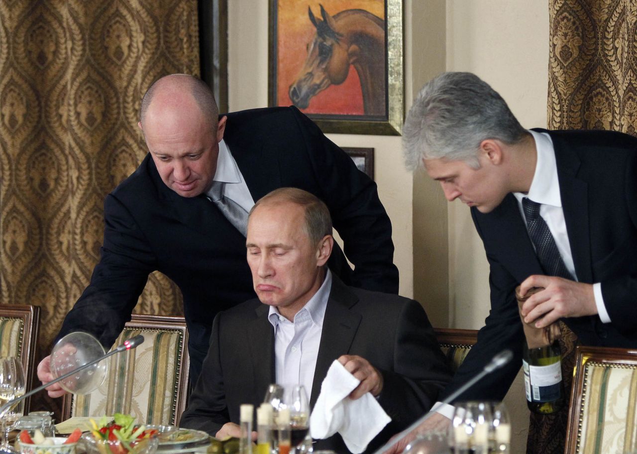 Prigozhin, left, serves food to Russian Prime Minister Vladimir Putin, center, during dinner at Prigozhin's restaurant outside Moscow, Russia in November 2011.